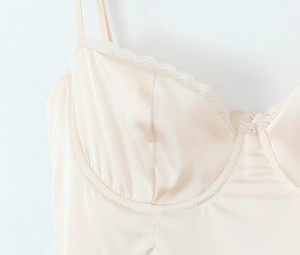 Close-up of champagne satin corset top with delicate white lace trim and slim straps
