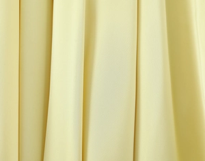 Macro detail of soft light yellow chiffon fabric showing elegant draping and fine texture
