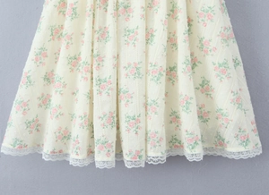 Détail du tissu à fleurs avec texture à pois 3D et bordure en dentelle blanche de la robe