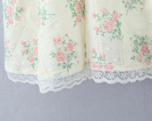 Détail de l'imprimé floral rose et du bord en dentelle blanche sur une robe d'été