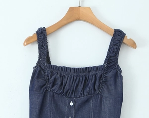 Detail of ruffle trim neckline and white buttons on dark blue denim camisole top