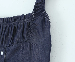 Detailed macro view of denim dress neckline with elastic smocking and white button