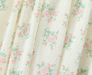 Vue détaillée du tissu floral crème avec roses roses et texture à pois suisses