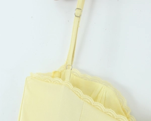 Detail of adjustable thin straps and delicate lace trim on light yellow french dress