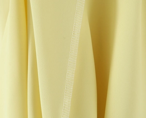 Macro shot of fine overlock stitching and yellow fabric texture on elegant dress