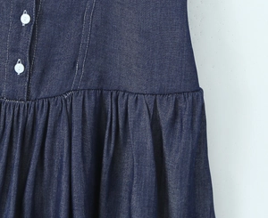 Detailed macro shot of dark blue denim fabric with white buttons and waist pleats