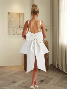 Détail de l'imposant nœud en satin blanc sur une robe courte dos nu chic