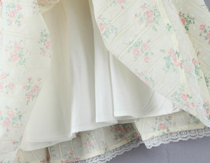 Détail de l'ourlet de robe fleurie avec motifs de roses roses et dentelle blanche fine