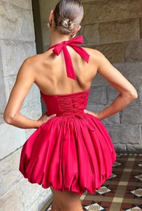 Detail view of red halter dress featuring a lace-up back and elegant bow tie design