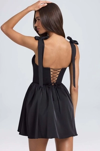Detail of corset-style back with criss-cross laces and satin bow straps on black dress