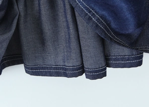 Close-up of dark blue denim dress hem with durable double-stitched sewing details