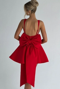 Détail d'une robe courte dos nu rouge avec un grand nœud décoratif et de longs rubans fluides