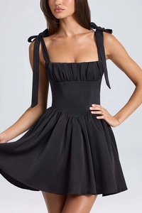 Detail view of black square neck dress with ribbon bows and pleated waist stitching