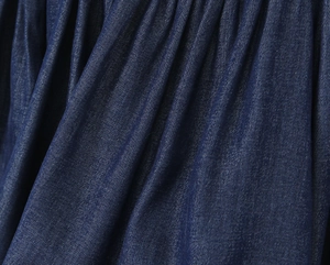 Close-up of deep blue denim fabric texture and soft pleats on a French style summer dress