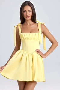 Detail of light yellow square neck dress with ribbon bow shoulder straps and pleated bust