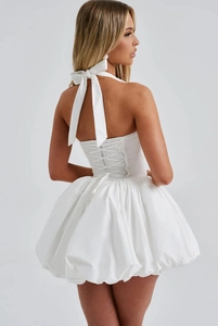 Detail of white halter neck dress featuring a large bow and criss-cross tie-back design