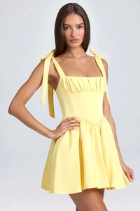 Detail of light yellow dress with bow-tie shoulder straps and pleated square neckline