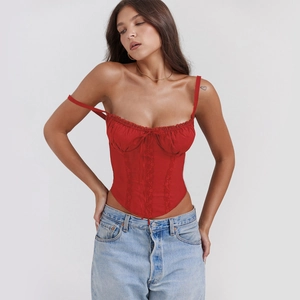 Macro detail of red slim fit corset top featuring lace trim and a delicate ribbon bow tie
