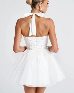 Close-up of white halter dress with cross-tied lace-up back and ruffled mesh skirt detail