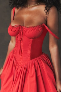 Detailed view of red corset dress featuring lace trim and front lace-up tie design