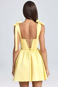 Detailed back view of yellow satin dress featuring adjustable bow straps and lace-up design