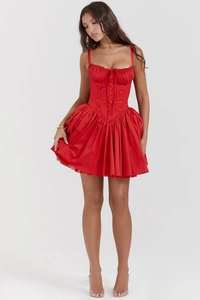 Detail of red corset mini dress with lace trim, pleated bust, and bow decoration