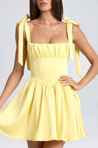 Detail of square neck yellow satin dress with ruffled chest and bow straps