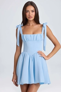 Detail of light blue mini dress featuring wide bow shoulder straps and pleated corset bodice