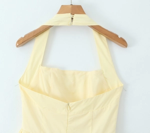 Dettaglio dell'abito giallo chiaro allacciato al collo con bottoni e zip invisibile sul retro