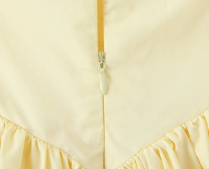 Dettaglio di un abito color crema stile francese con cerniera nascosta e tessuto a pieghe