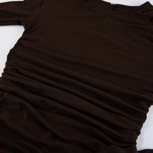 Close-up detail of dark brown ruched fabric and gathered side seam on long sleeve dress
