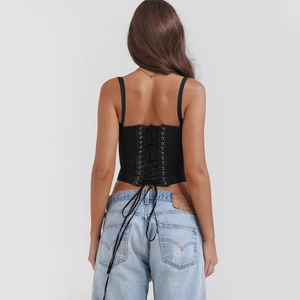 Detail view of the black corset top featuring a lace-up crisscross back with metal eyelets