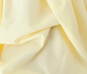 Dettaglio della trama del tessuto giallo crema e pieghe naturali dell'abito aderente