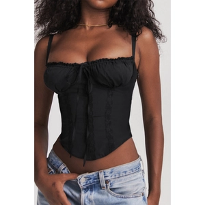 Detail of black corset top featuring lace ruffles, bow tie, and slim fit boning structure