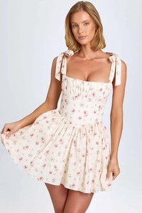 Detailed close-up of bow-tie shoulder straps and ruffled bust on floral mini dress