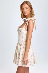 Close-up of pink rose floral print and bow tie shoulder straps on white summer dress
