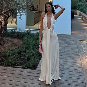 Detail of white halter neck maxi dress featuring deep V-neck and ruched waist design