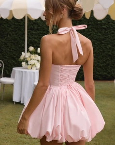 Detail of light pink halter dress showing the bow tie neck, open back, and puffy hemline