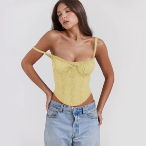 Detail of light yellow lace corset top featuring gathered bust and pointed hemline