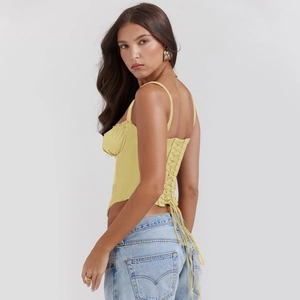 Detailed back view of a yellow corset top with lace-up crisscross straps and pointed hem