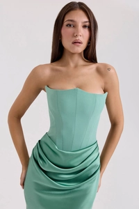 Close-up of mint green corset bodice and shiny satin pleated skirt of a party dress