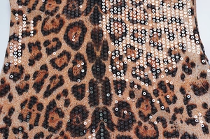 Close-up of leopard print fabric with shimmering silver sequins and lace stitching details