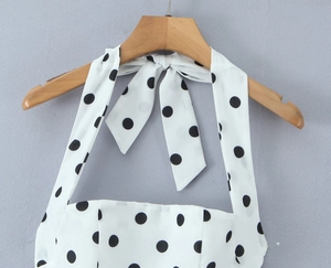 Détail d'un haut dos nu blanc à pois noirs avec un nœud papillon attaché au niveau du col