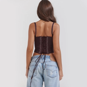 Detail of dark brown corset top featuring criss-cross lace-up back and slim fit design