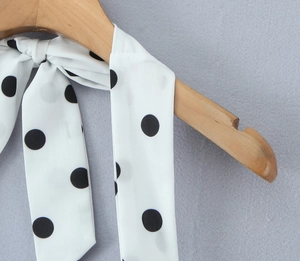 Détail d'une robe dos nu en mousseline blanche à pois noirs avec col à nouer