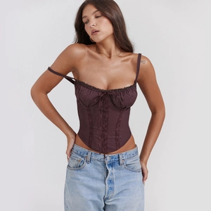 Close-up of lace-up corset top in dark brown with intricate lace patchwork and bow detail