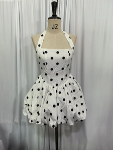 Detail of halter neck bow dress with black polka dots on white fabric and bubble hem