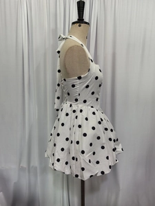 Side view of a white halter dress with black polka dots and a puffy skirt on a mannequin
