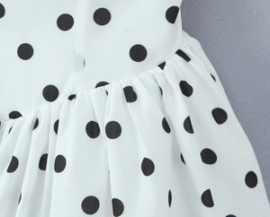 Détail du tissu blanc plissé à pois noirs d'une robe d'été dos nu élégante