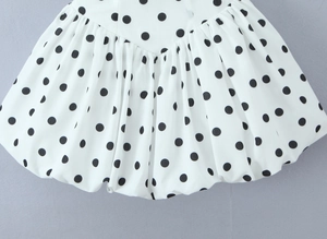 Détail de l'imprimé à pois noirs sur tissu blanc avec texture plissée chic français